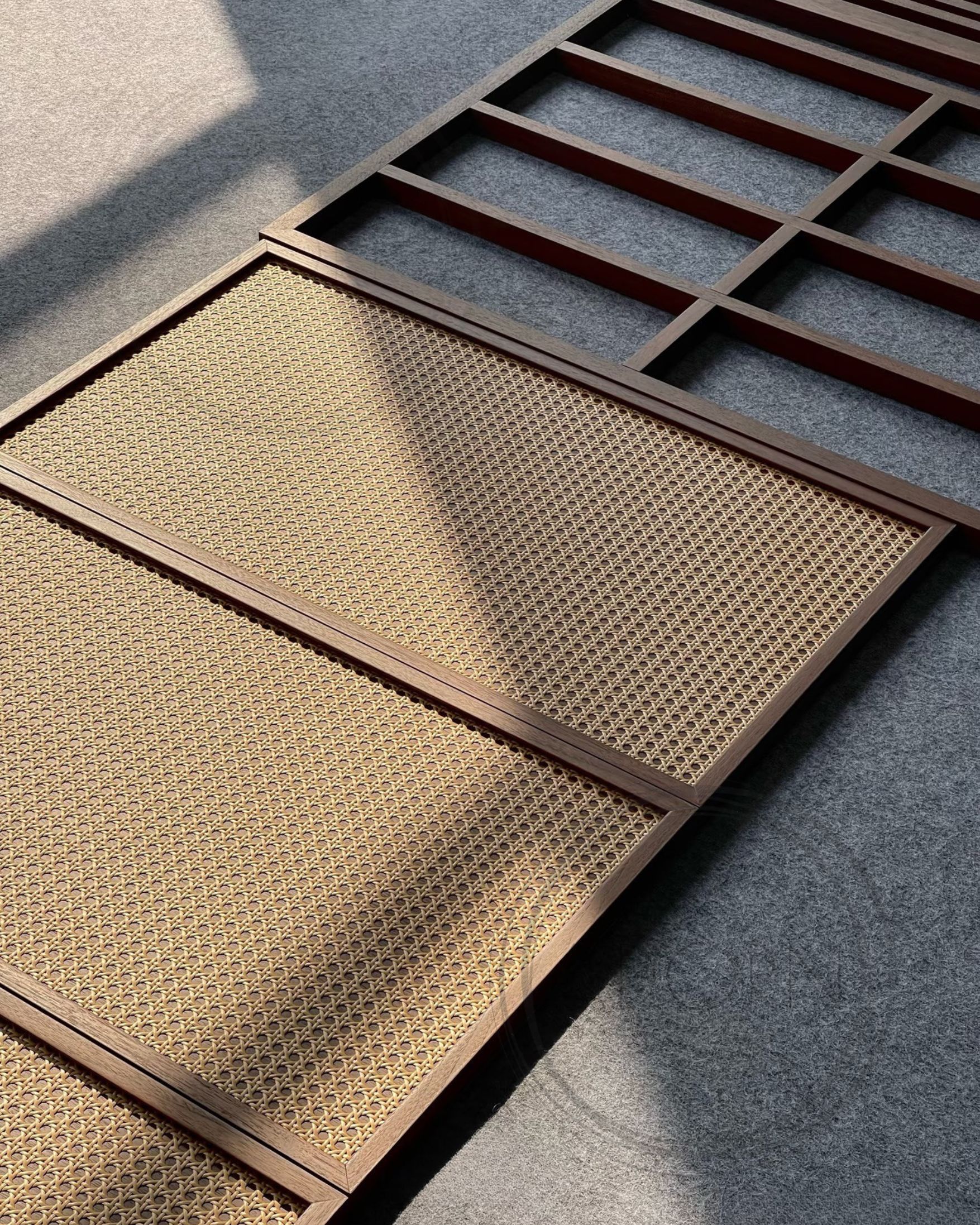 Walnut cabinetry frames with woven cane panels, lit by raking daylight