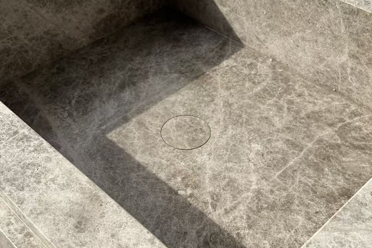 Free-standing vanity carved from a single slab of Tundra Grey marble
